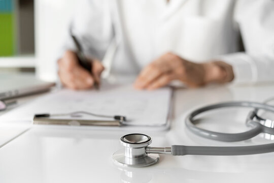 Close-up of doctor medical professional wearing uniform taking notes, physician, therapist or practitioner filling medical documents, writing prescription for patient. Health care, medicine concept