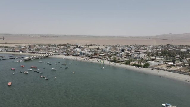 Locals enjoy sunny beach day in Peruvian port town in chala desert
