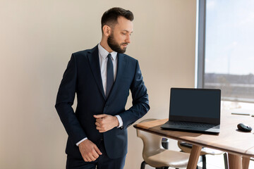 businessman in a modern stylish office next to a laptop in a business suit