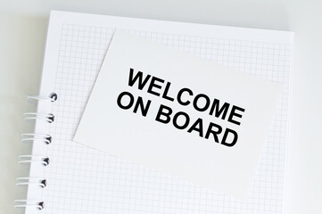 welcome on board text on a white card on a table with notepad in isolation