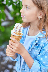 Cute girl liccking and eating italian ice cream cone while resting in park on summer day