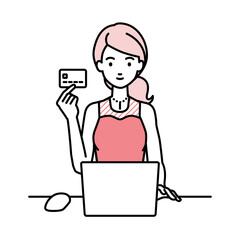 デスクで座ってPCを使いながらクレジットカードを手に持っているドレスの女性