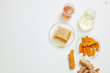 Honey and turmeric decorated with transparent podium and beaker test tube with blank space in white laboratory background for experiment advertising , top view 