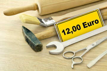 Werkzeug und gelbes Schild mit 12,00 Euro Mindestlohn in Deutschland