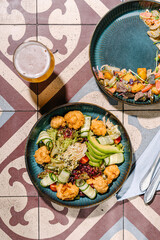 Salad with fried fish, avocado, tomatoes, cucumbers and herbs. salad with stewed veal cheeks, potato wedges, tomatoes and mustard sauce