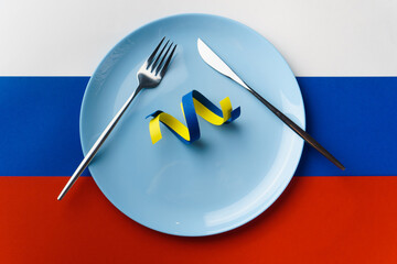 Blue and yellow ribbons as symbol of Ukraine on plate on Russian flag. Russia want to eat Ukraine