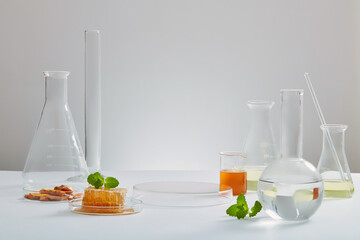 Honey and turmeric decorated with transparent podium and beaker test tube with blank space in white laboratory background for experiment advertising , front view
