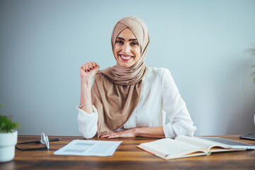 Entrepreneurship For Islamic Women. Portrait of happy muslim businesswoman in hijab with papers at home office workplace, copy space
