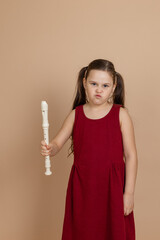 Girl in red dress with displeased expression hold common flute in hand, beige background. Learning...