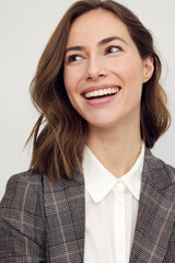 Close-up portrait of beautiful young businesswoman looking happy and confident to the left. Big smile on her face, looking beautiful and cheerful standing isolated on white background.