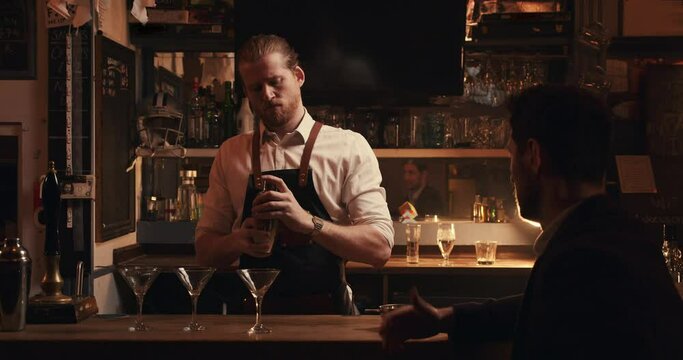 Caucasian male bartender mixing drinks behind the bar making cocktails