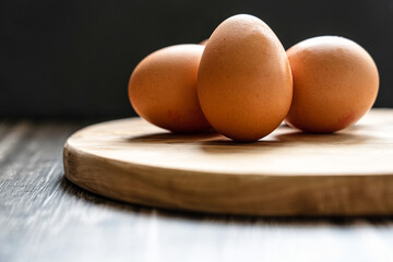 Fresh eggs on wooden table, black background
