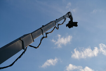 Crane broadcasting TV camera sistem used for filming from above, photographed against blue sky