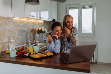 Lesbian couple having video call via laptop at home
