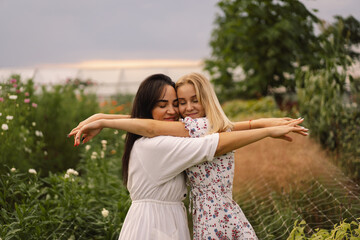 Obraz premium Happy mother's day. A young mother with a teenage daughter spends time in the garden. Mom and her daughter teenage girl are playing, smiling and hugging. Loving single mother hugs cute daughter.