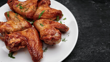Grilled chicken wings on a plate, on a dark background