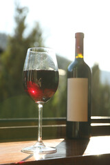 Glass and bottle of wine stands on wooden windowsill