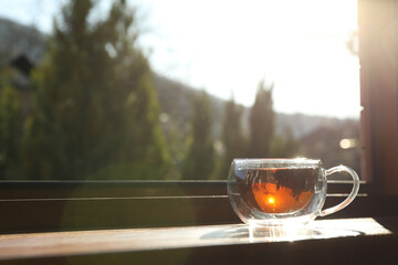 Cup of tea stands on wooden windowsill