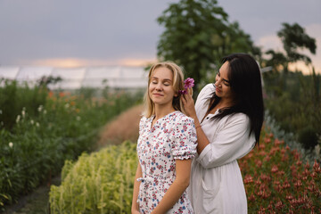 Happy mother's day. A young mother with a teenage daughter spends time in the garden. Mom braiding her daughter's hair. Family holiday and togetherness. Loving single mother hugs cute daughter.