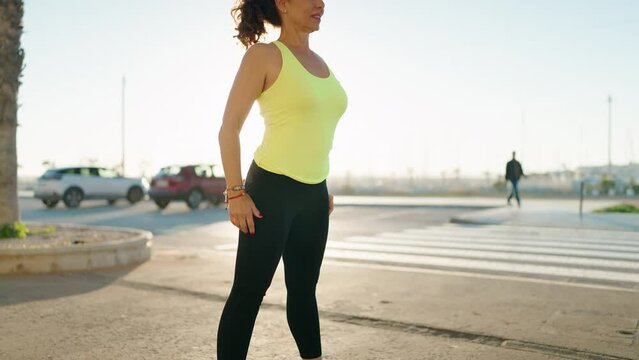 Middle age woman wearing sportswear training legs exercise at street
