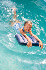 Happy little girl having fun in the swimming pool, dives and swim,