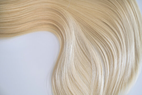 Curl female healthy hair. Concept hairdresser spa salon. strand of blond silky hair on a white background.