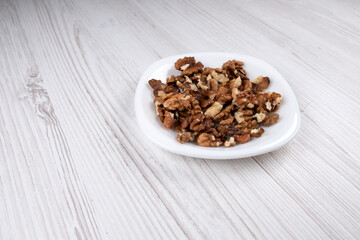 Walnuts on a white plate, side view. A plate of nuts on the table. Healthy food. Man's health.