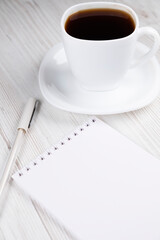 A cup of coffee, a notebook and a white pen on a wooden table. Office work