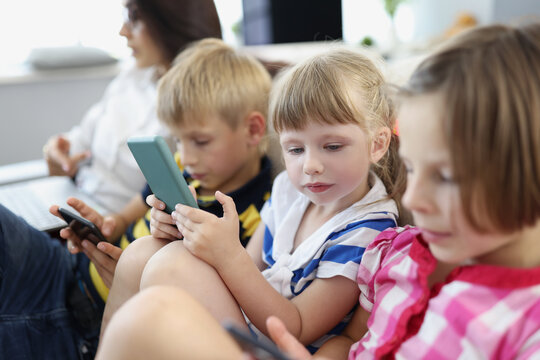 Children at home, stare at smartphone screens, addiction to modern technologies