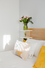 Bouquets of flowers in vases on a headboard at sunset in bedroom