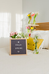 Welcome spring sign with vintage chalkboard on a white bed on wooden headboard
