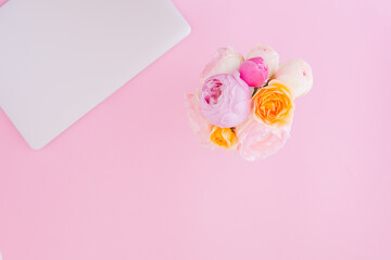 Aerial view with pink background and laptop with bouquet of delicate flowers