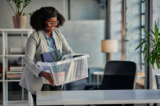 Young woman carrying office supplies in plastic box