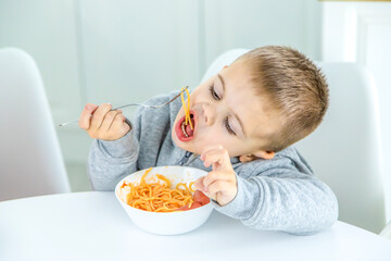 children in the kitchen at the table turning pasta.