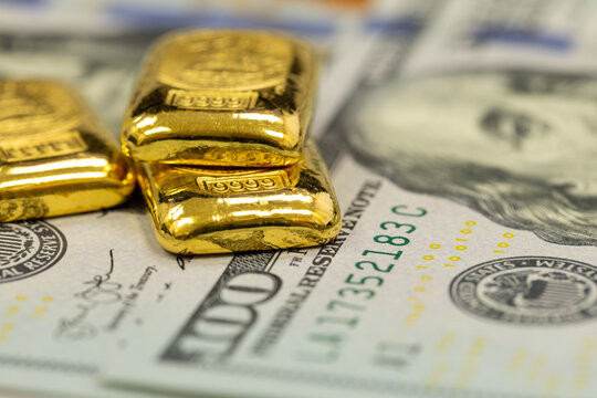 pile of pure gold bars, bullion, ingot on background of US dollar banknotes