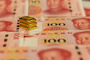 pile of pure gold bars, bullion, ingot on background of Renminbi, or RMB, CNY, currency of China. Set of one hundred yuan. Chinese money. Business concept