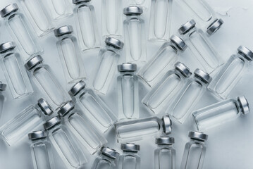 Glass medical ampoule vial for injection. Medicine is dry white drug penicillin powder or liquid with of aqueous solution in ampulla. Close up. Bottles ampule with aluminum cap on backgrounds gray.