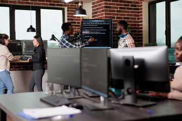 Cyber security company developers encrypting cloud processing data system using blockchain technology. Cybernetics engineers reviewing lines of code in order to secure mainframe database storage.