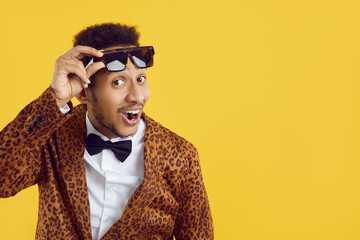 Happy positive handsome black man in funky leopard outfit, bowtie and sunglasses smiling and...