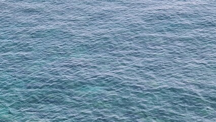 Savona, Italy - February 12, 2022: Panorama of the blue sea, light above the water, ocean sunrise. Some little waves in winter days. Clear sky reflected on the water.