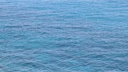 Savona, Italy - February 12, 2022: Panorama of the blue sea, light above the water, ocean sunrise. Some little waves in winter days. Clear sky reflected on the water.