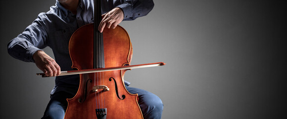 Cello player or cellist performing in an orchestra background