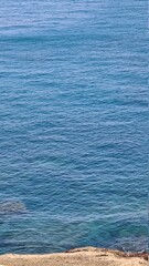 Obraz premium Savona, Italy - February 12, 2022: Panorama of the blue sea, light above the water, ocean sunrise. Some little waves in winter days. Clear sky reflected on the water.