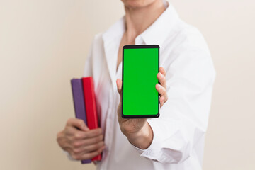 Woman hands holding books and smartphone with blank green screen background