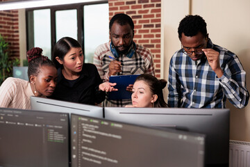 Informational agency multiracial tech engineers programming application while using computer. Cyber...