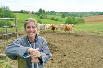 Smiling woman breeder in field, livestock in background