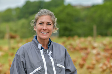 Smiling breeder woman standing in farm, herns in background