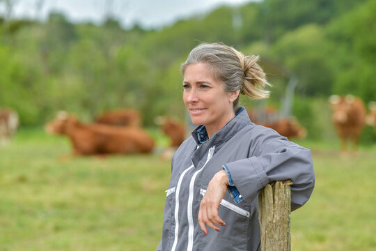 Smiling Breeder Woman Standing In Farm, Livestock In Background