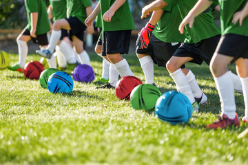 Row of kids soccer players with colourful balls on training grass pitch. Children playing sports...