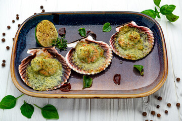 Scallops baked in a shell with cheese and pesto sauce